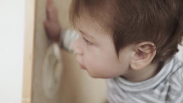 Малыш выглядывает за дверь — стоковое видео
