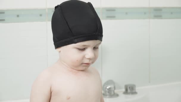 Niño en un baño con gorra — Vídeos de Stock