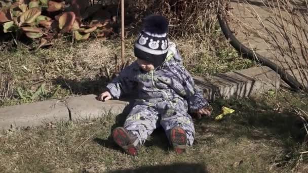 Niño en overoles se encuentra en la hierba — Vídeos de Stock