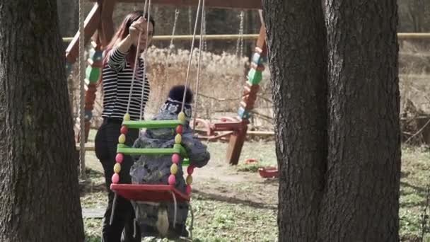 Girl rolls a child on a swing — Stock Video