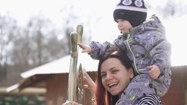 Menino nos ombros da mãe vira — Vídeo de Stock