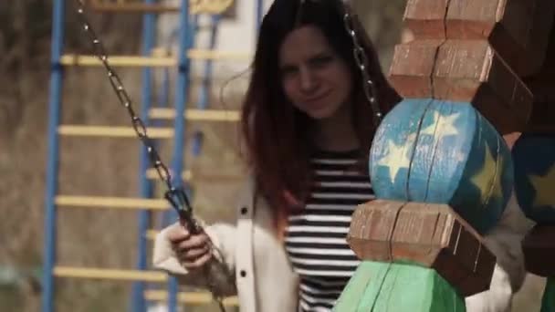 Menina montando um balanço em um playground — Vídeo de Stock