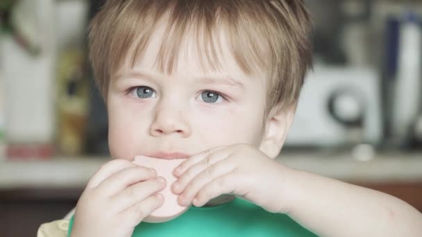 Хлопчик їсть варену ковбасу — стокове відео