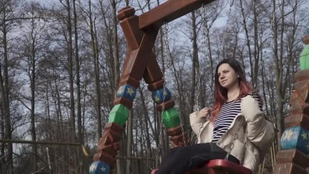 Chica montando un columpio en un parque infantil — Vídeos de Stock