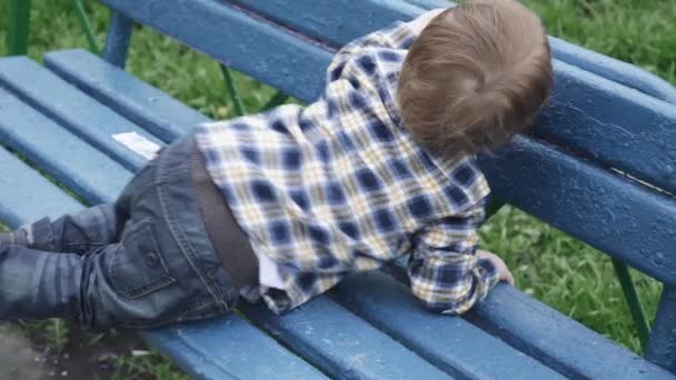 Criança em uma camiseta sobe um banco — Vídeo de Stock