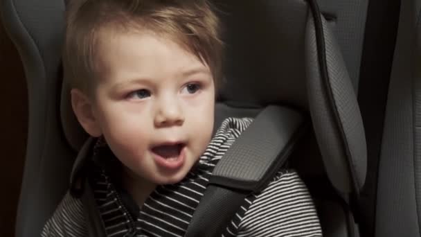 Baby boy sits on a child seat in the car — Stock Video
