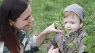 Palto giyen çocuk yapraklarla oynuyor.