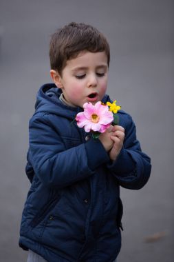 Bir çocuk çocuk elinde tutan ve çiçekler Bahar üzerinde bir parkta keşfetmek.