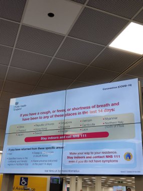 01/03/2020 - Luton Airport, United Kingdom - Coronavirus warning/alert screen in the arrival hall. 