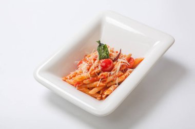 Derin beyaz bir tabak içinde Parmesan peyniri serpilir domates soslu Penne makarna