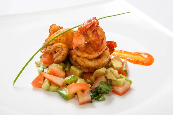 Fried shrimps on fried vegetables on a white plate