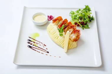 Kızarmış karides beyaz tabakta soslu patates püresi ile taze marul ile süslenmiş. Stir Fry karides.