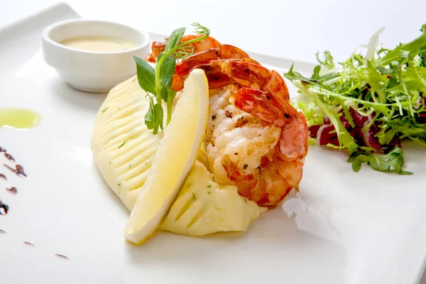 Fry karides karıştırın. Kızarmış karides beyaz tabakta soslu patates püresi ile taze marul ile süslenmiş