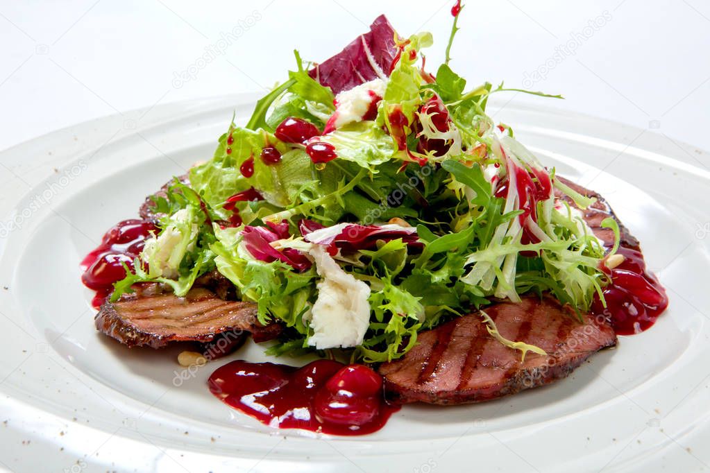 Salad with grilled veal and fresh salad leaves on a white plate