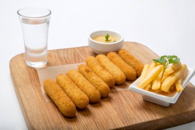 Balık sopalarla bir ahşap tahta üzerine sos ve patates kızartması ile