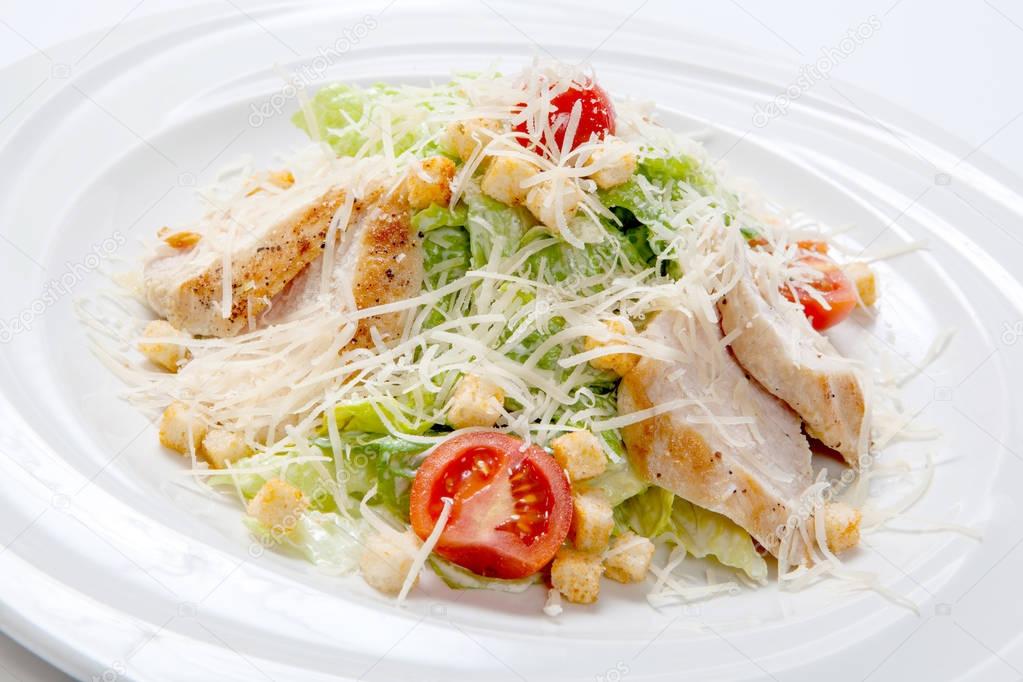 Caesar salad with chicken on a white round plate