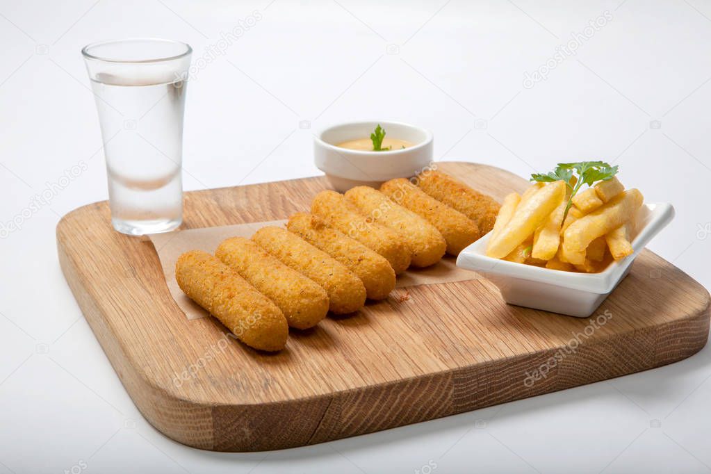 Fish sticks on a wooden board with sauce and fried potatoes