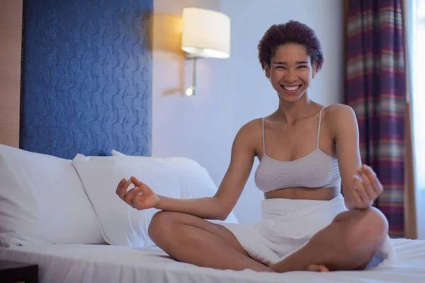 Young black woman doing yoga at home in the lotus position.