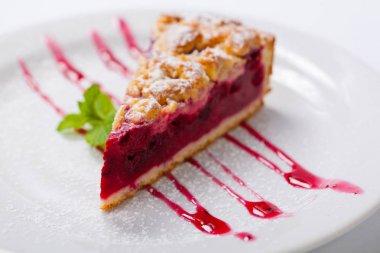 Kiraz kek çatal ile beyaz plaka üzerinde yeşil nane ile. Vişneli tart