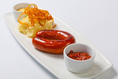 Sosisli patates ve beyaz tabakta lahana turşusu ile