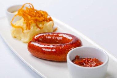 Sosisli patates ve beyaz tabakta lahana turşusu ile