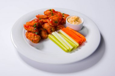 Havuç ve kereviz sopalarla rokfor sos daldırma ile süslenmiş plaka üzerinde oturan kanatları baharatlı Barbekü buffalo tavuk