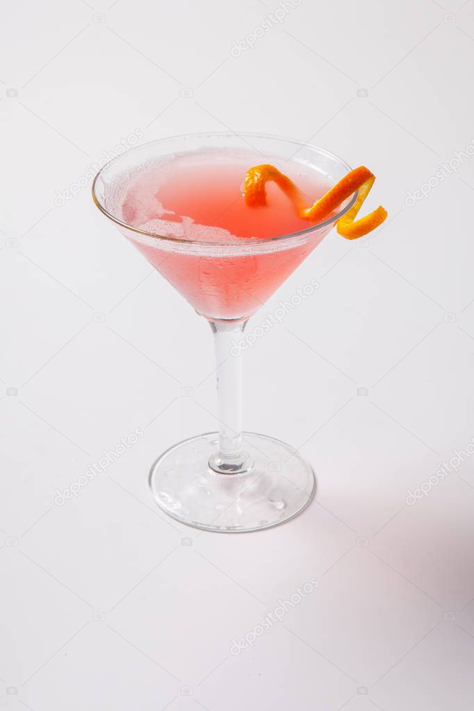 Red cocktail with orange garnish on a whithe background