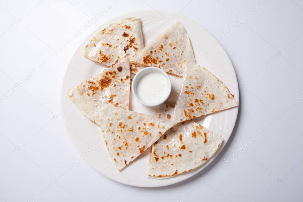 quesadilla with beef and chicken on a white plate. quesadilla and sauce.