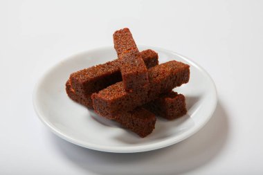 Kavrulmuş sarımsaklı kruton, siyah ekmek beyaz bir plaka üzerinde.