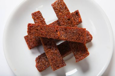 Kavrulmuş sarımsaklı kruton, siyah ekmek beyaz bir plaka üzerinde.