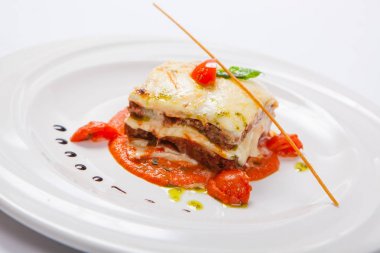 Ot ve domates soslu beyaz tabakta lazanya