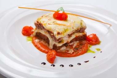 Ot ve domates soslu beyaz tabakta lazanya