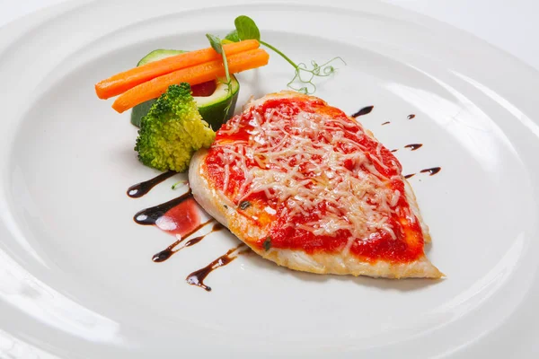 Grilled Chicken breasts coated with melted cheese, vegetables and tomato sauce on a white plate — Stock Photo, Image