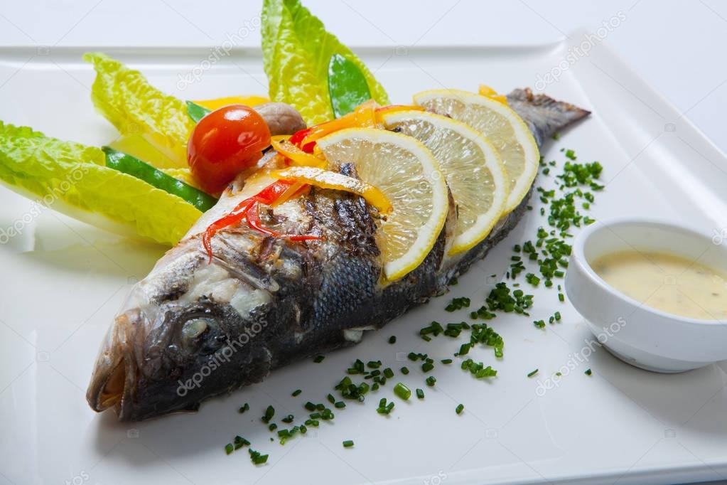 Grilled whole fish decorated with leaves of lettuce and cherry tomato, served with garlic sauce. Fried whole fish