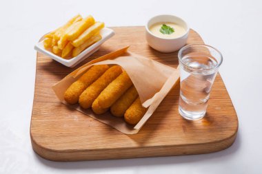 Balık sopalarla bir ahşap tahta üzerine sos ve patates kızartması ile