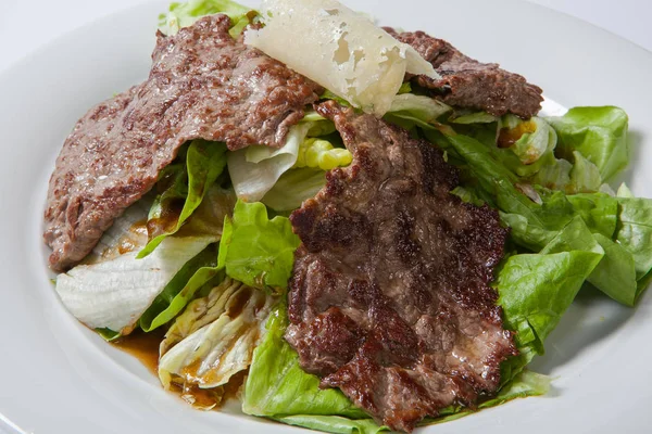 Говяжий салат с салатом и сыром на белой тарелке — стоковое фото
