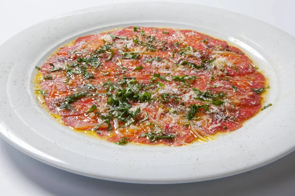 Carpaccio de carne servida com rúcula em um prato branco — Fotografia de Stock