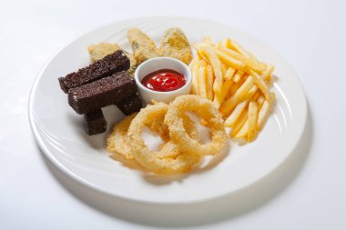 Taze bira aperatifler ürün yelpazesine beyaz tabakta. Patates kızartması, kruton ve kabak ve soğan halkaları.