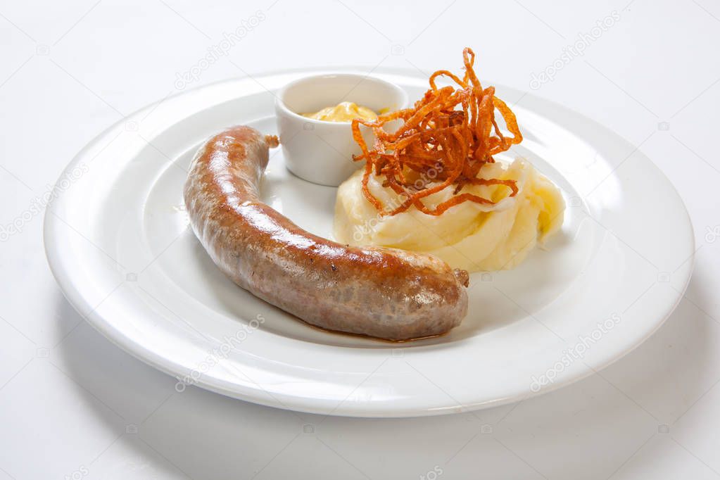 Mashed potato and roasted sausage or bratwurst on white plate