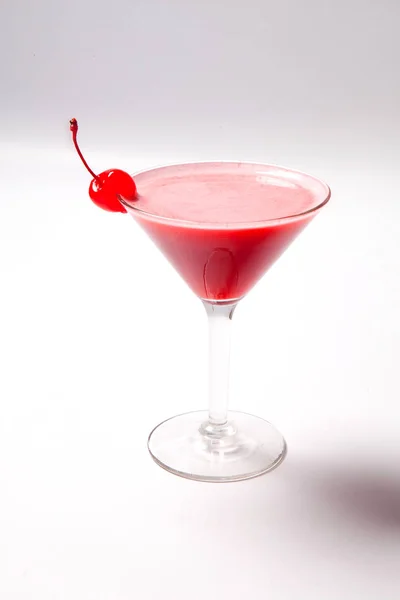 Boisson rouge en verre de martini, garnie de cerise au marachino. sur fond blanc — Photo