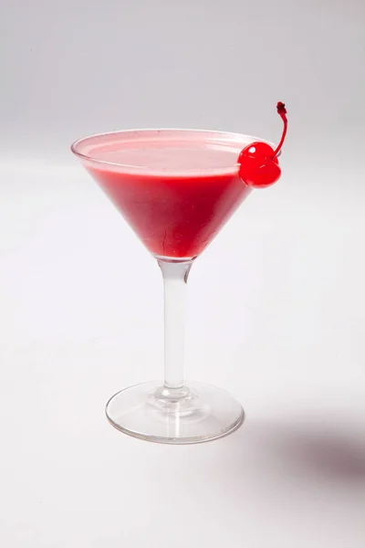 Boisson rouge en verre de martini, garnie de cerise au marachino. sur fond blanc — Photo