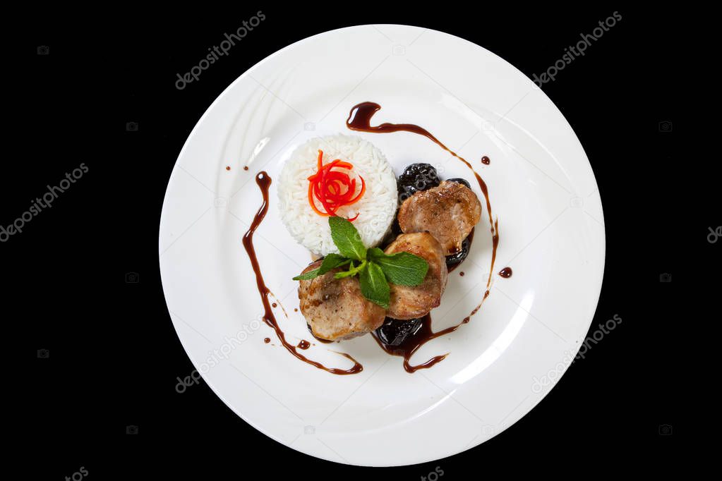Pork medallions steak with prunes sauce on a white plate