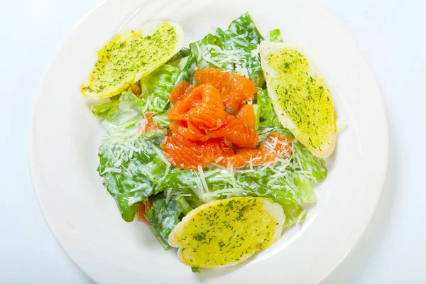 Свежий салат Цезарь с лососем на белой тарелке — стоковое фото