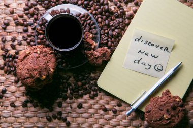 kahve fincanı ve etiket üzerinde mesaj ile çerezleri ve Not Defteri ile ahşap masa üzerinde kahve çekirdekleri