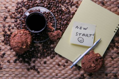 kahve fincanı ve etiket üzerinde mesaj ile çerezleri ve Not Defteri ile ahşap masa üzerinde kahve çekirdekleri