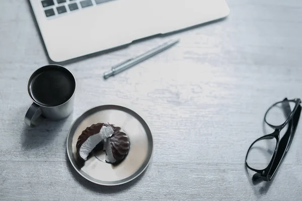 Biurko biuro z laptopa, pióro i i okulary i kawa, ciasteczka i słodycze — Zdjęcie stockowe