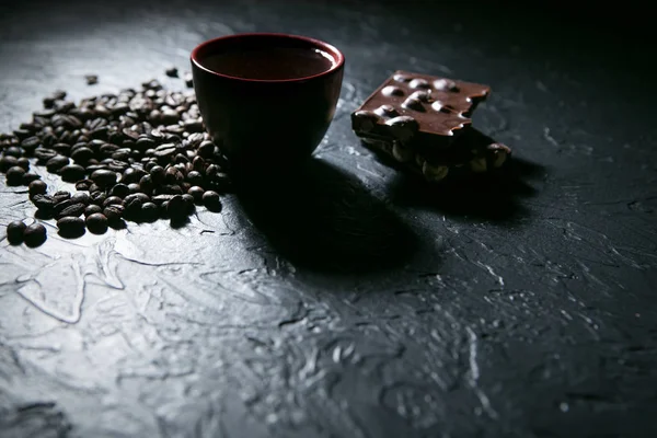 Kaffekopp og kaffebønner og sjokolade på svart bakgrunn – stockfoto