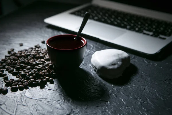 Taza de café y granos de café y pan de jengibre y portátil sobre fondo negro — Foto de Stock