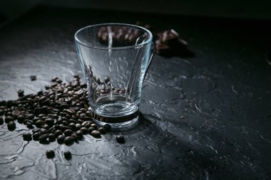 Boş kahve fincanı ve siyah arka plan üzerine kahve çekirdekleri