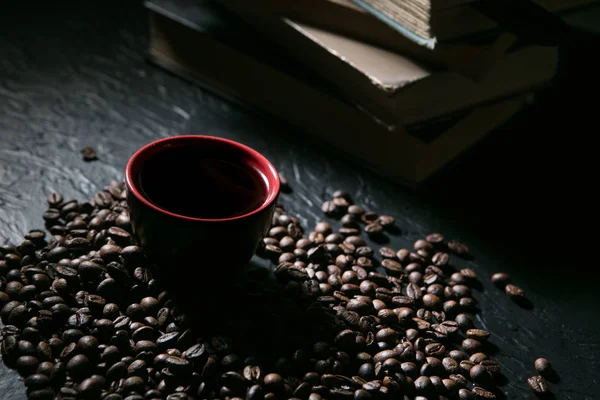 Coffee cup and coffee beans on the background of books — Stock Photo, Image